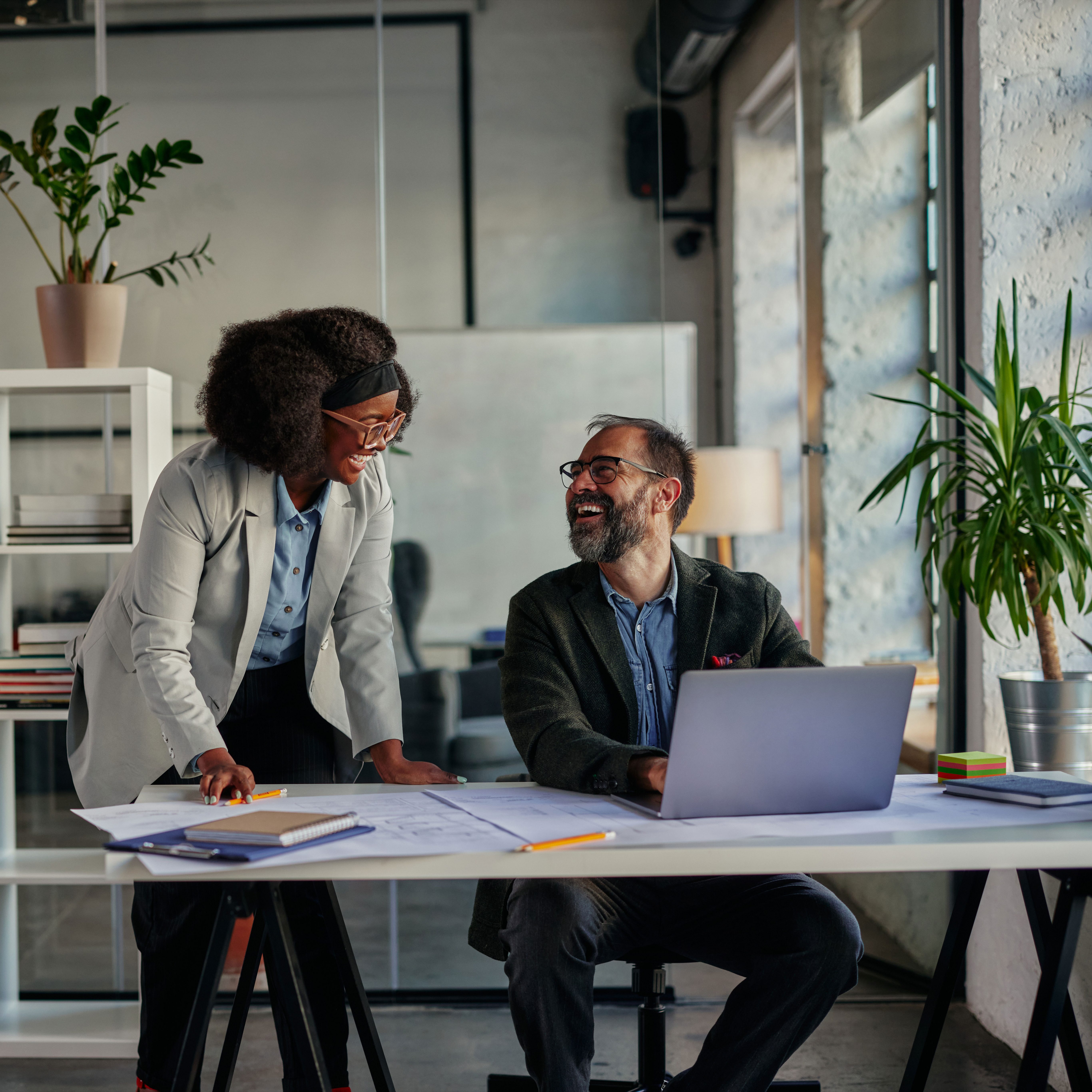 Two business people discussing new business project at a desk in an open office.